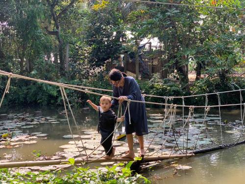 a woman and a child crossing a bridge over a river at Saigon Garden Homestay in Ho Chi Minh City