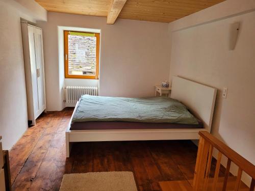 a bedroom with a bed and a window and wooden floors at Casa Antica Corte in Giumaglio