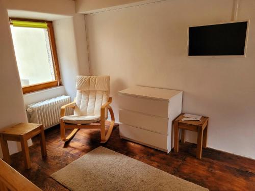 a room with a chair and a dresser and a television at Casa Antica Corte in Giumaglio