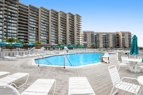 a swimming pool with white chairs and a large building at Sea Colony - 4003 Volley in Bethany Beach