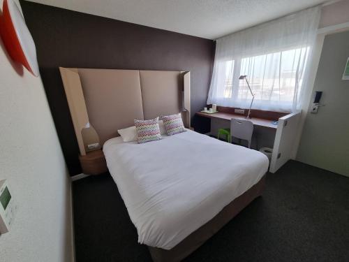 a bedroom with a large white bed and a desk at Campanile Toulouse - Blagnac Aéroport in Blagnac