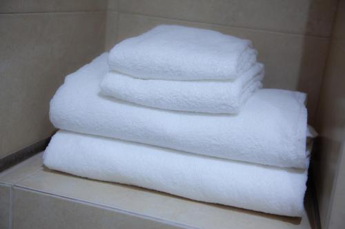 - une pile de serviettes blanches sur une étagère dans une salle de bains dans l'établissement Noches en Triana, à Séville