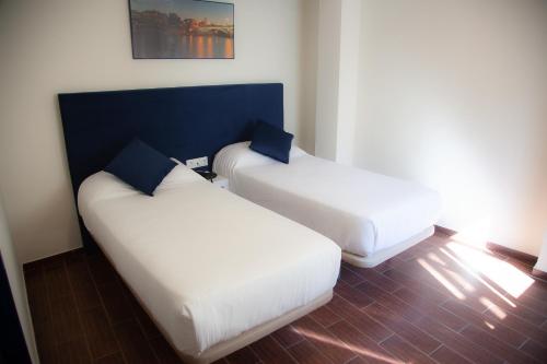two white beds in a room with a blue wall at Noches en Triana in Seville