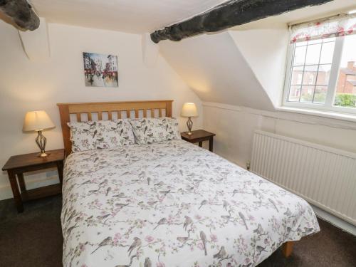 a bedroom with a bed and two windows at Rose Cottage in Upton upon Severn