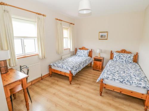 a bedroom with two beds and a desk at 8 Lios Na Sioga in Belmullet