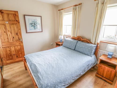 a bedroom with a bed and two windows at 8 Lios Na Sioga in Belmullet
