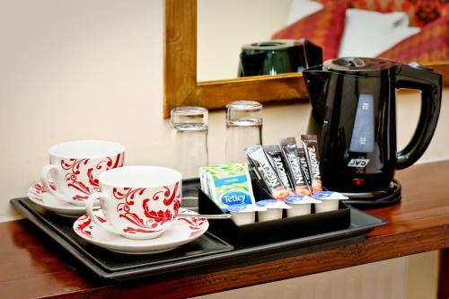a tray with two cups and a coffee pot on a table at Leigh House Hotel in London