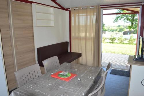 mesa de comedor y sillas en una habitación con ventana en Chalet -Glory-, en Casteljaloux