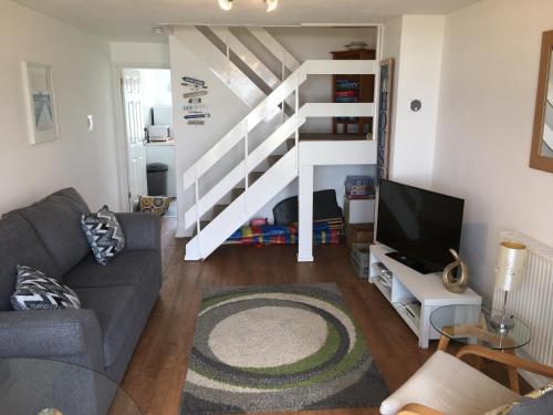 a living room with a couch and a staircase at 34 Surfview Beach House in Newquay
