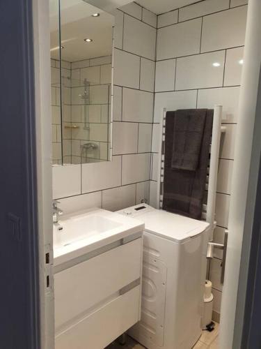 une salle de bain blanche avec un lavabo et un miroir dans l'établissement petit coin ensoleillé, à Beausoleil