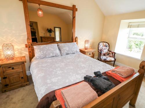a bedroom with a large bed with a dog laying on it at Whispering Willows - The Thatch in Craigtown