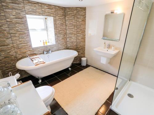 a bathroom with a tub and a toilet and a sink at Whispering Willows - The Thatch in Craigtown