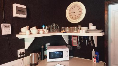 a counter with a microwave and a clock on a wall at Furrows Lodge in Nieu-Bethesda