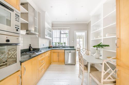 a kitchen with wooden cabinets and a white table and chairs at ALTIDO Elegant 2-bed, 2 bath flat with private terrace in South Kensington, close to tube in London