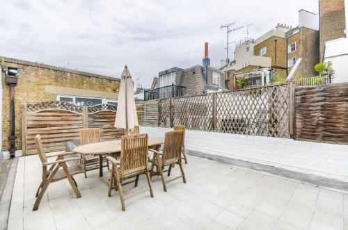 a patio with a table and chairs and an umbrella at ALTIDO Elegant 2-bed, 2 bath flat with private terrace in South Kensington, close to tube in London