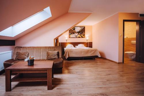 a hotel room with a bed and a couch at Villa Skomanda in Augustów