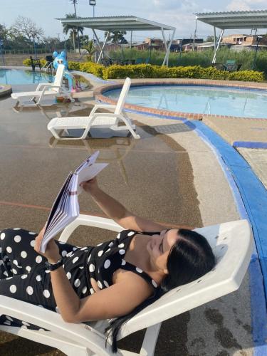 a woman laying in a chair reading a book by a pool at GUADUALES DEL CAFÉ B-409 in Montenegro