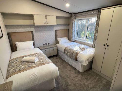 a small bedroom with two beds and a window at Blue Bell Lodge with Hot Tub Malton in Little Habton