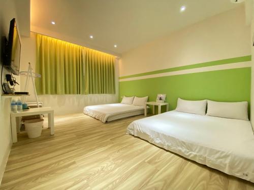 a bedroom with two beds and a green wall at Ji Apartment in Tainan