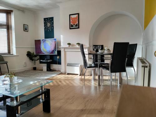 a living room with a table and chairs and a television at Cheerful Gem of Barking & Dagenham 3 Bedroom House Entire Property in Goodmayes