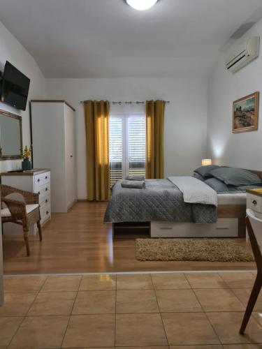 - une chambre avec un lit, un bureau et une télévision dans l'établissement Apartments Marijan, à Orebić
