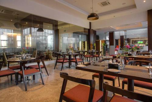 a restaurant with wooden tables and chairs and flowers at Crowne Plaza Nairobi Airport by IHG in Nairobi