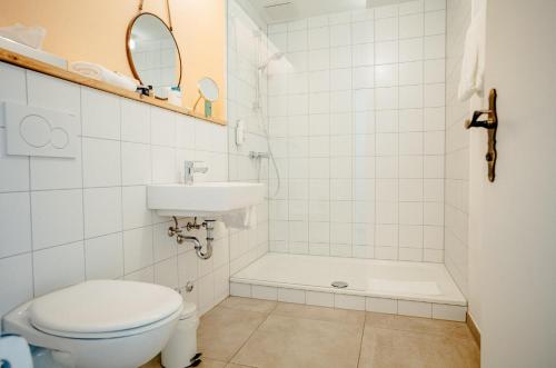 a white bathroom with a toilet and a sink at Alpenrose Bayrischzell Hotel in Bayrischzell