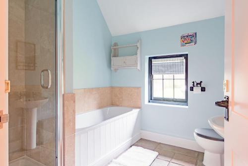 a bathroom with a tub and a toilet and a sink at The Kennels by Bloom Stays in Faversham