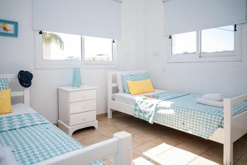 a bedroom with two beds and two windows at Protaras View Villas in Protaras