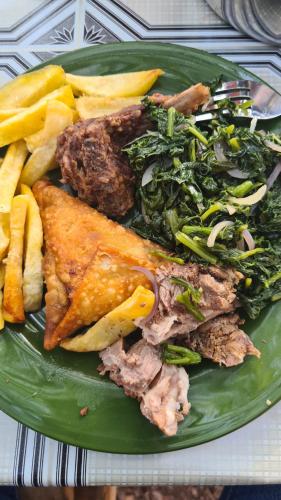 un plato de comida con carne y verduras y patatas fritas en Chagga farm house, en Moshi