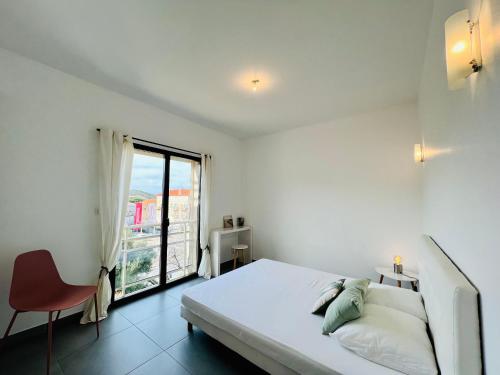 une chambre blanche avec un lit et une fenêtre dans l'établissement Jardins de Quatrina centre ville, à Propriano