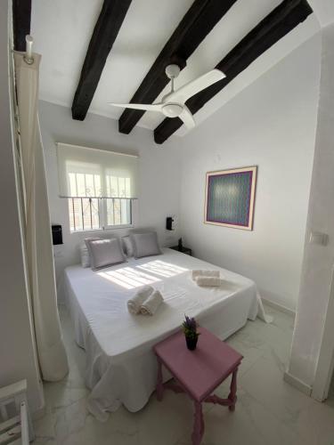 Un dormitorio blanco con una cama grande y una mesa en PETRA, en Denia