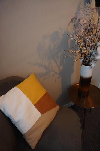 a pillow and a table with a vase of flowers at Bed and Breakfast Kik en Bun in Katwijk aan Zee