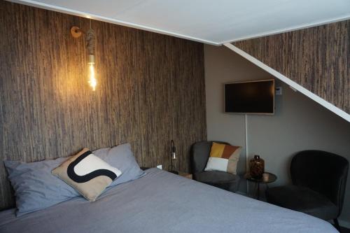 a bedroom with a bed and two chairs and a tv at Bed and Breakfast Kik en Bun in Katwijk aan Zee