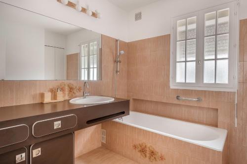 ein Badezimmer mit Waschbecken, Badewanne und Spiegel in der Unterkunft 150m de la plage, vue mer, maison pour 6 in Sarzeau