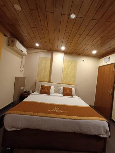 a large bed in a room with a wooden ceiling at Aalcajars Inn in Patna
