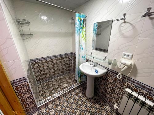 Un baño con lavabo, ducha y espejo. en Shukrona Guest house, en Bukhara