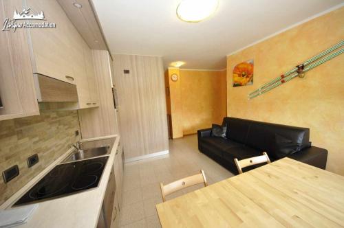 cocina y sala de estar con sofá negro en Baita Carosello Apt 4 Adiacente Carosello 3000, en Livigno