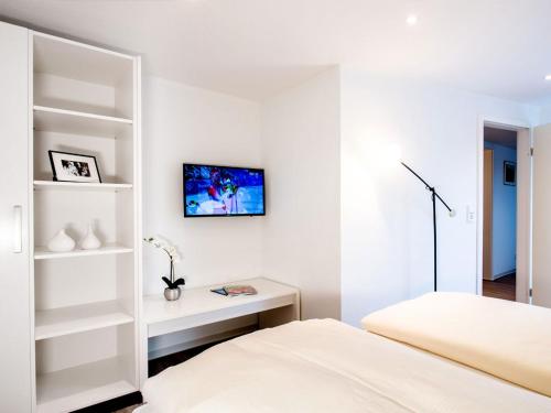 a white bedroom with a bed and a desk at Hotel Busch in Westerstede