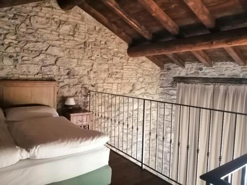 a bedroom with a bed and a stone wall at Cascina Belvedì in Clanezzo