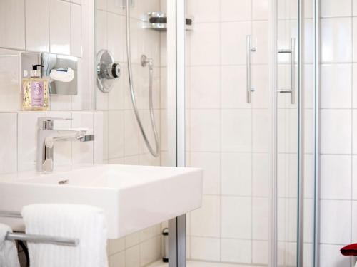 a white bathroom with a sink and a shower at Hotel Busch in Westerstede