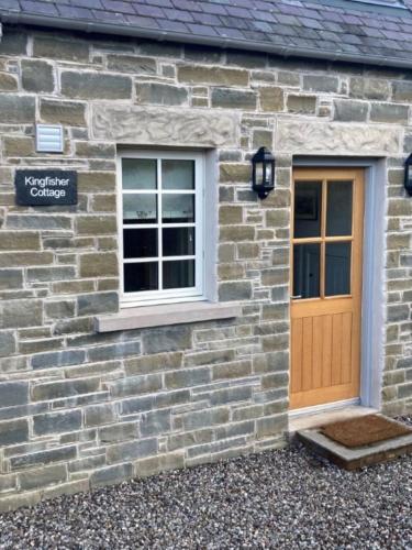 a stone cottage with a door and a window at Kingfisher Cottage, Port o Tay in Pitlochry
