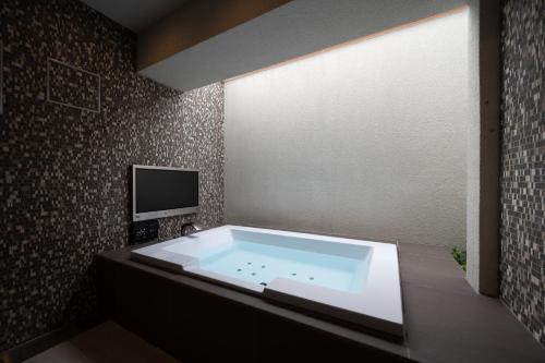 a bath tub with a television in a bathroom at hotel brattostay ホテル ブラットステイ in Hachioji