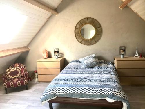 - une chambre avec un lit, un miroir et une chaise dans l'établissement Maison au coeur d'une écurie, à Sennevières