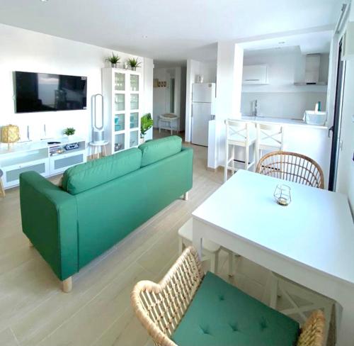 a living room with a green couch and a kitchen at SUNRISE ESQUINZO, paraíso de sol & playa & paz in Playa Jandia