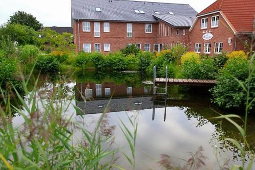 a body of water with a bridge and a building at Landhotel Möllhagen in Schülp