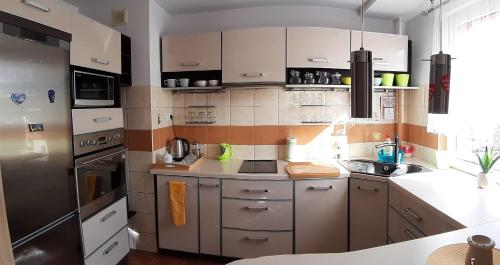 a kitchen with white cabinets and a stainless steel refrigerator at Apartament Hetmańska in Wałbrzych