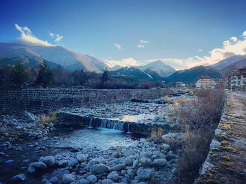a river with a waterfall and mountains in the background at CEDAR LODGE NEXT TO LIFT ONE BEDROOM APARTMENT in Bansko