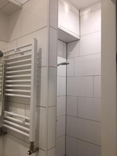 eine weiß geflieste Wand im Bad mit Dusche in der Unterkunft Butterfly in Groningen