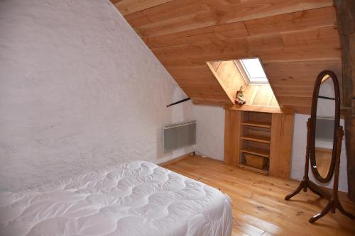 um quarto no sótão com uma cama e uma janela em Chez Maman em Beugnon